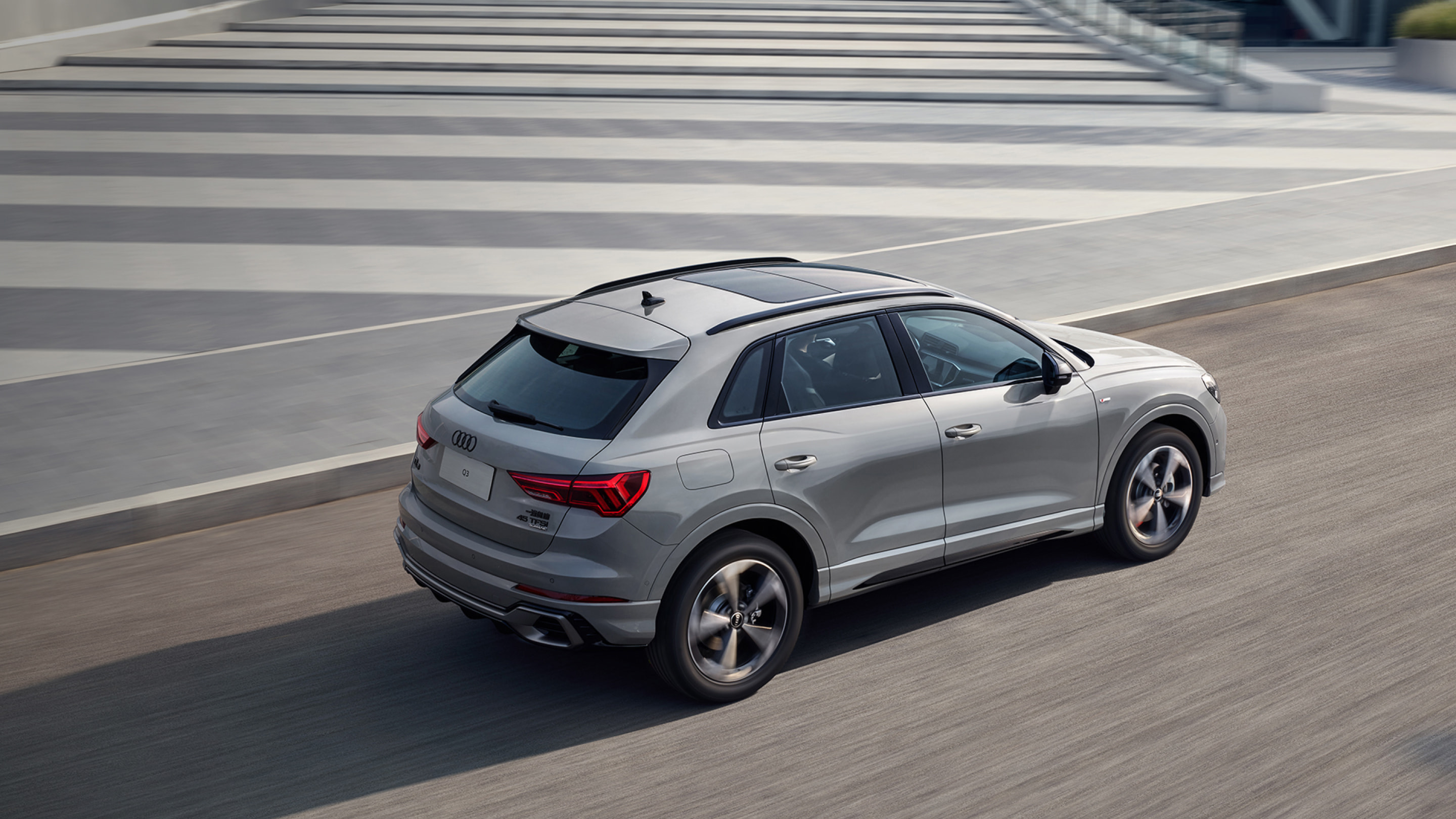 صورة ديناميكية لطراز Audi Q3 لعام 2026 من الجهة اليمنى، بلون فضي، على طريق TownCar.
