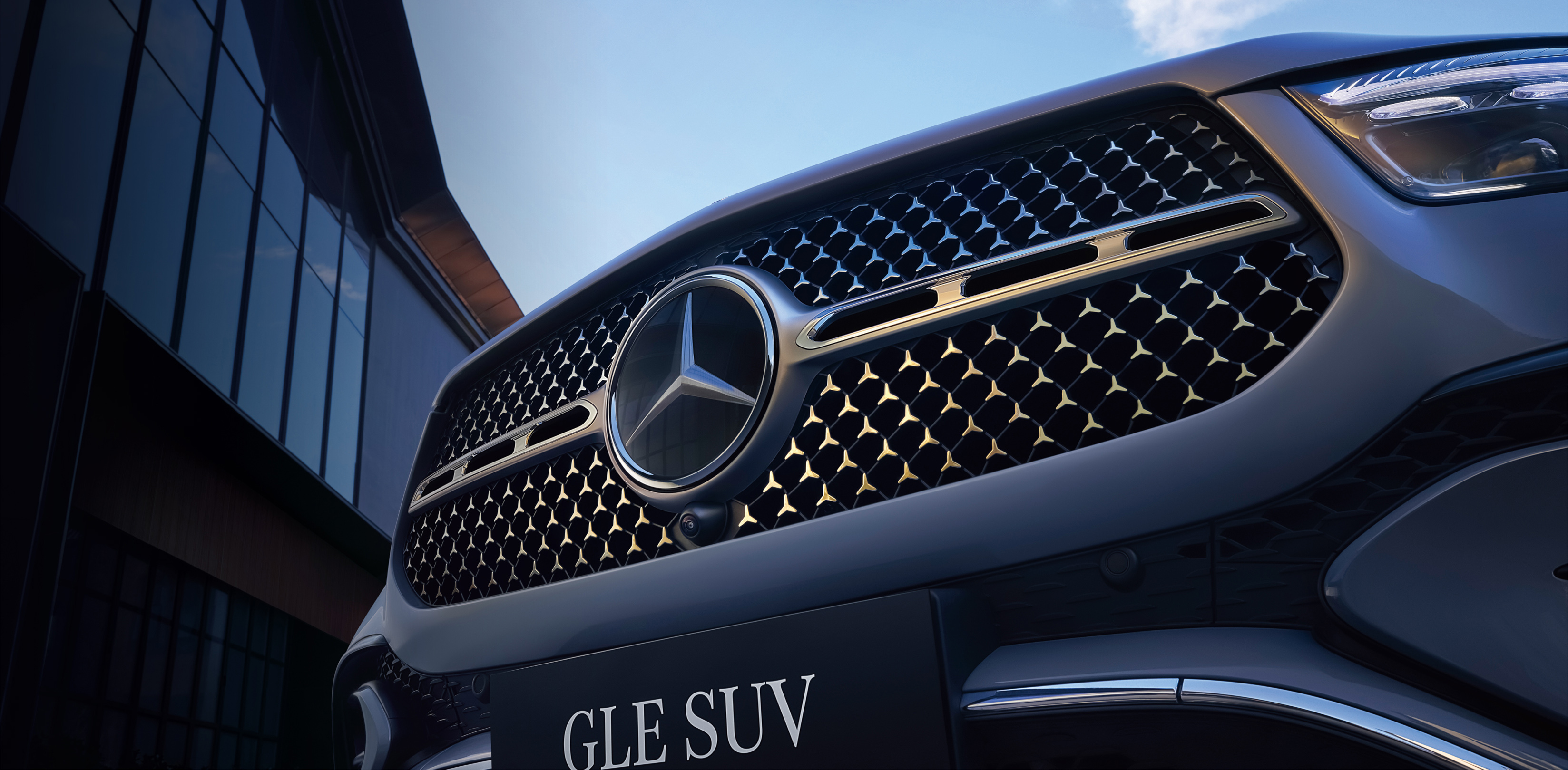 صورة قريبة لسيارة مرسيدس GLE SUV لعام 2026 باللون الأسود اللامع، مع خلفية من المباني الحضرية والسماء الزرقاء