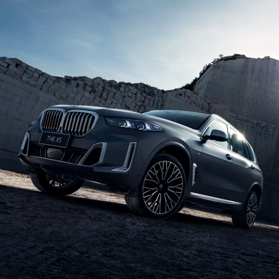 عرض أمامي لسيارة BMW BMW X5 طراز ٢٠٢٣ باللون الأسود على خلفية مبنى TownCar والسماء الزرقاء