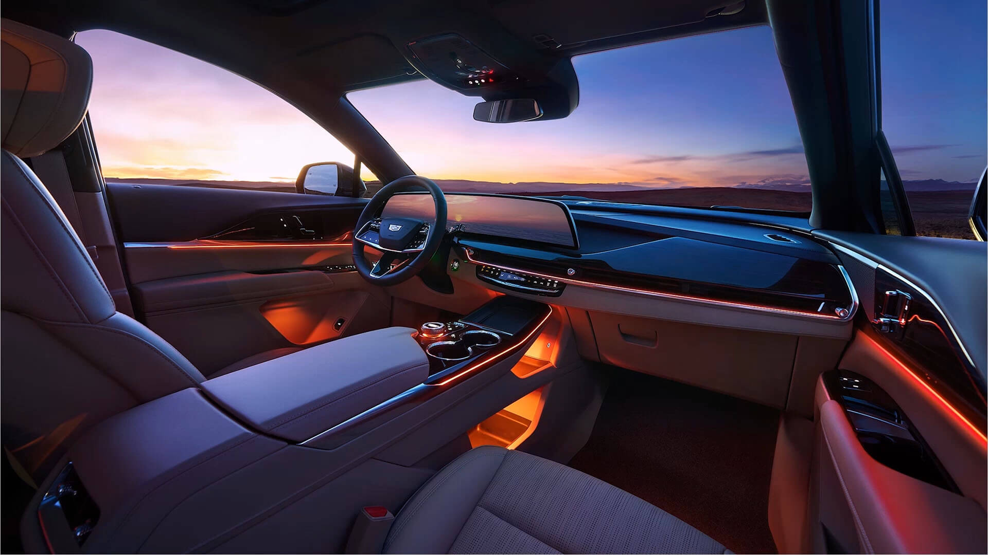 Vue intérieure du Cadillac XT5 2026, montrant le poste de conduite et le tableau de bord, avec en arrière-plan un paysage naturel au coucher du soleil.