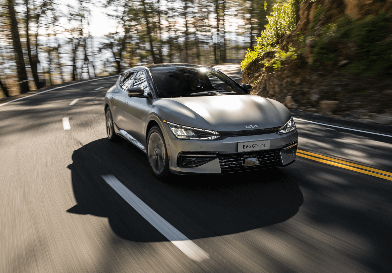 2026 KIA EV6 Silver Sedan Driving on a Forest Road