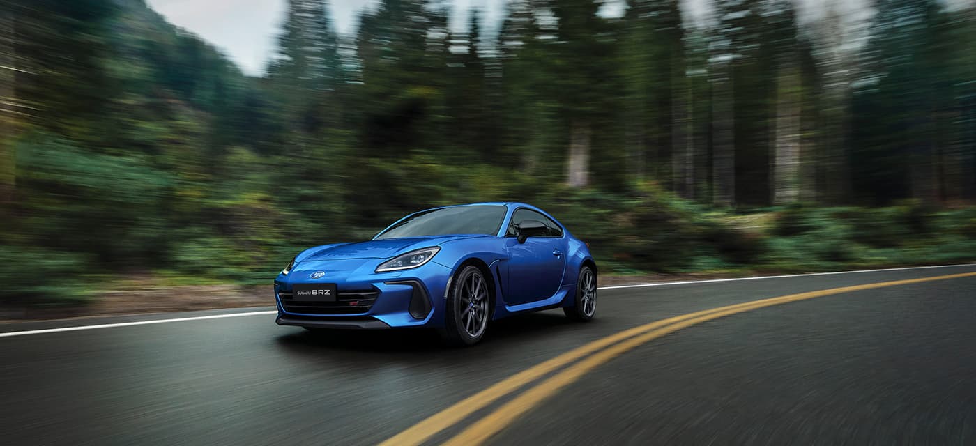 سيارة Subaru BRZ STI Sport لعام ٢٠٢٦ بلون أزرق تسير على طريق غابي