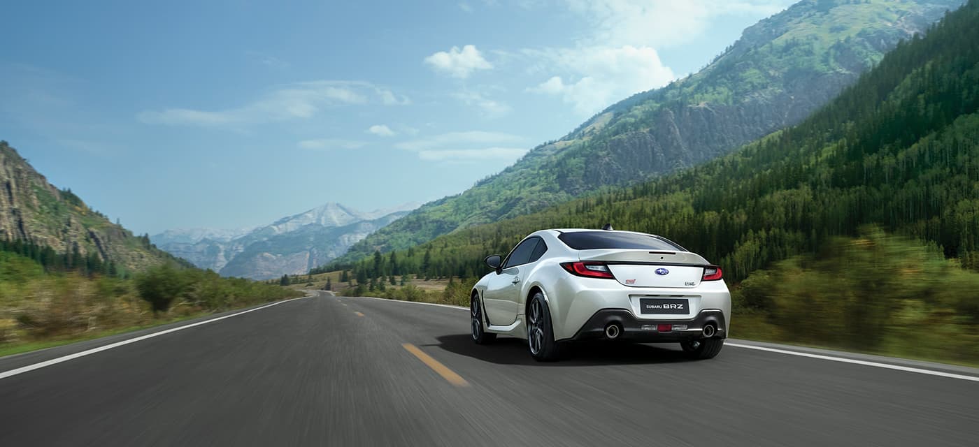 斯巴鲁SUBARU BRZ STI Sport 2026款白色跑车在蓝天白云和绿色山脉背景下行驶中的侧视图