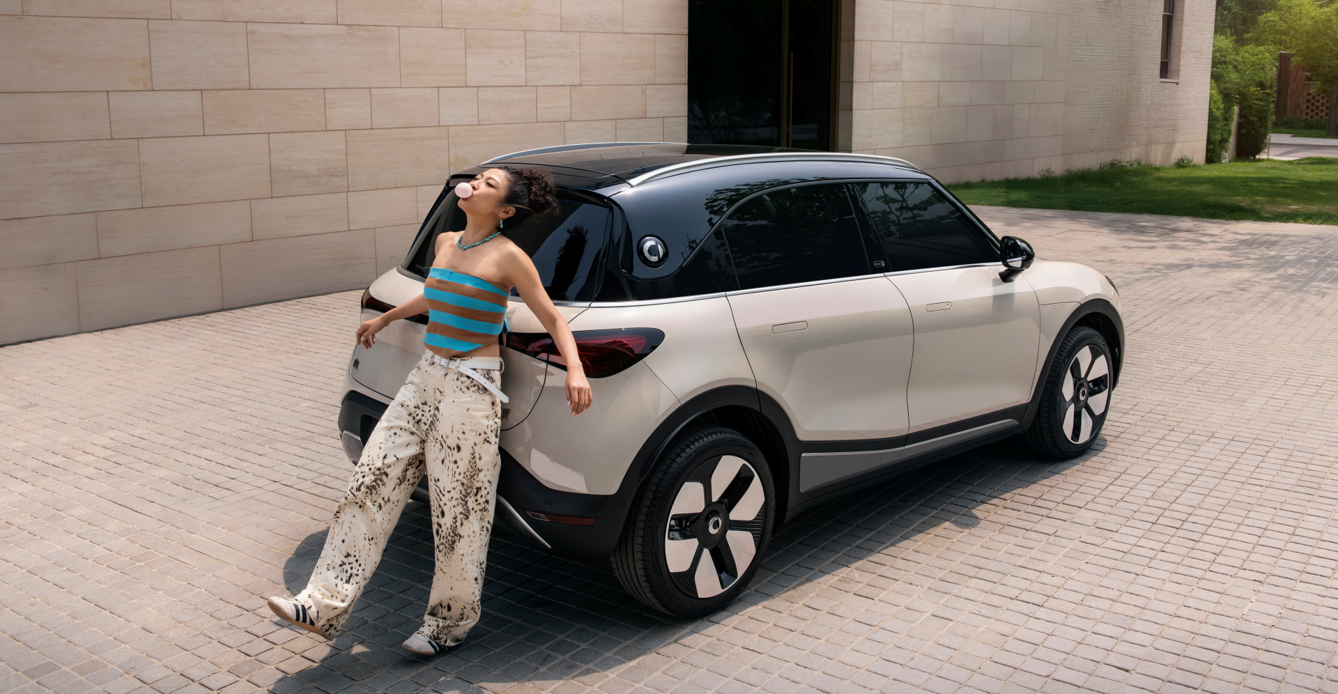 Static full-body photo of the white 2026 smart #1 taken from the right side, set against an outdoor urban backdrop.